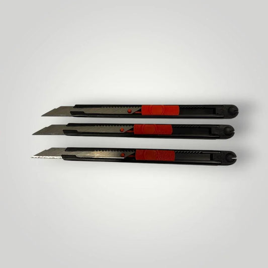 Drei schwarze Allzweckmesser mit roten Griffen auf hellem Hintergrund, ideal für Folienmontage