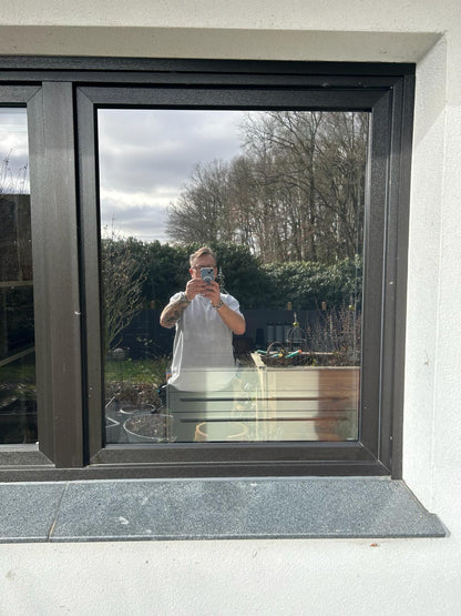 Reflektion eines Mannes in moderner Fensterfolie, Außenansicht, Garten und Bäume im Hintergrund