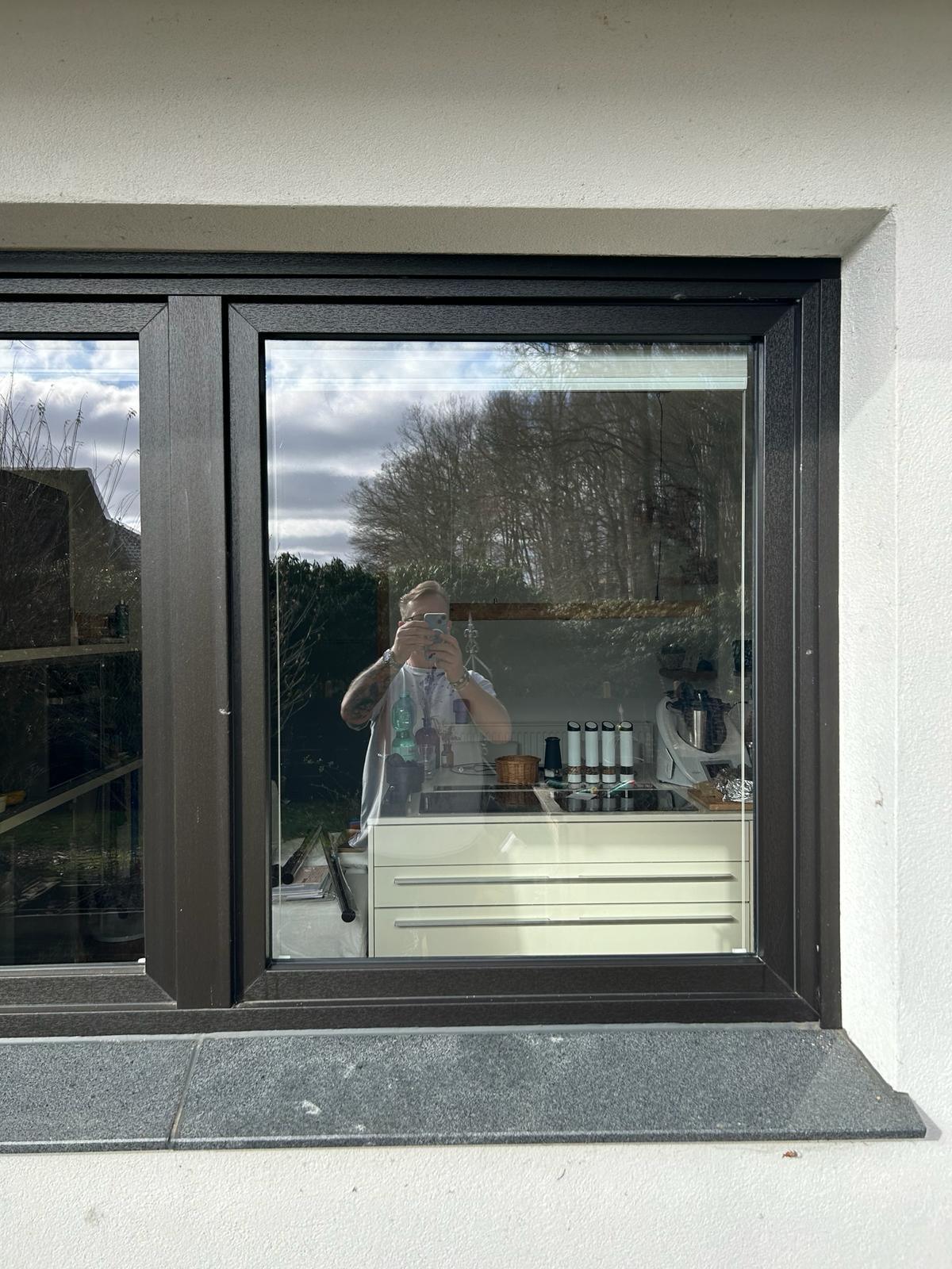 Fenster mit schwarzem Rahmen, klare Reflexion, Blick in moderne Küche, Außenbereich sichtbar