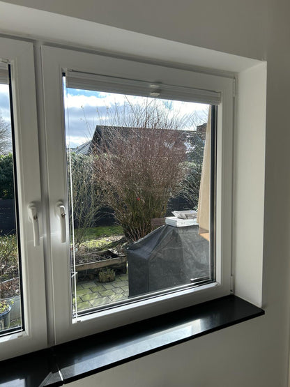 Doppelfenster mit weißem Rahmen, Blick auf Garten mit Terrasse und Grill, sonniger Tag