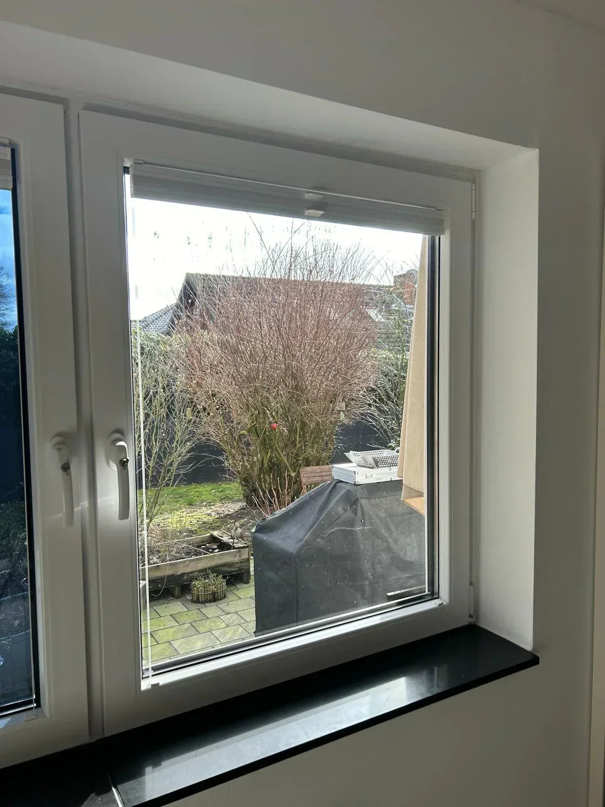 Fenster mit transparenter Fensterfolie und Blick auf Garten im Tageslicht