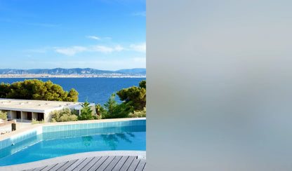 Mattgraue Fensterfolie zeigt Sichtschutz am Fenster mit Ausblick auf Pool, Meer und Berge