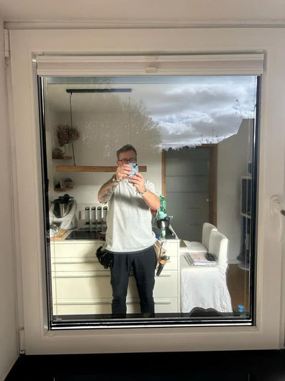 Reflektierende Fensterfolie auf Fenster, Spiegelung eines Mannes im Innenraum sichtbar