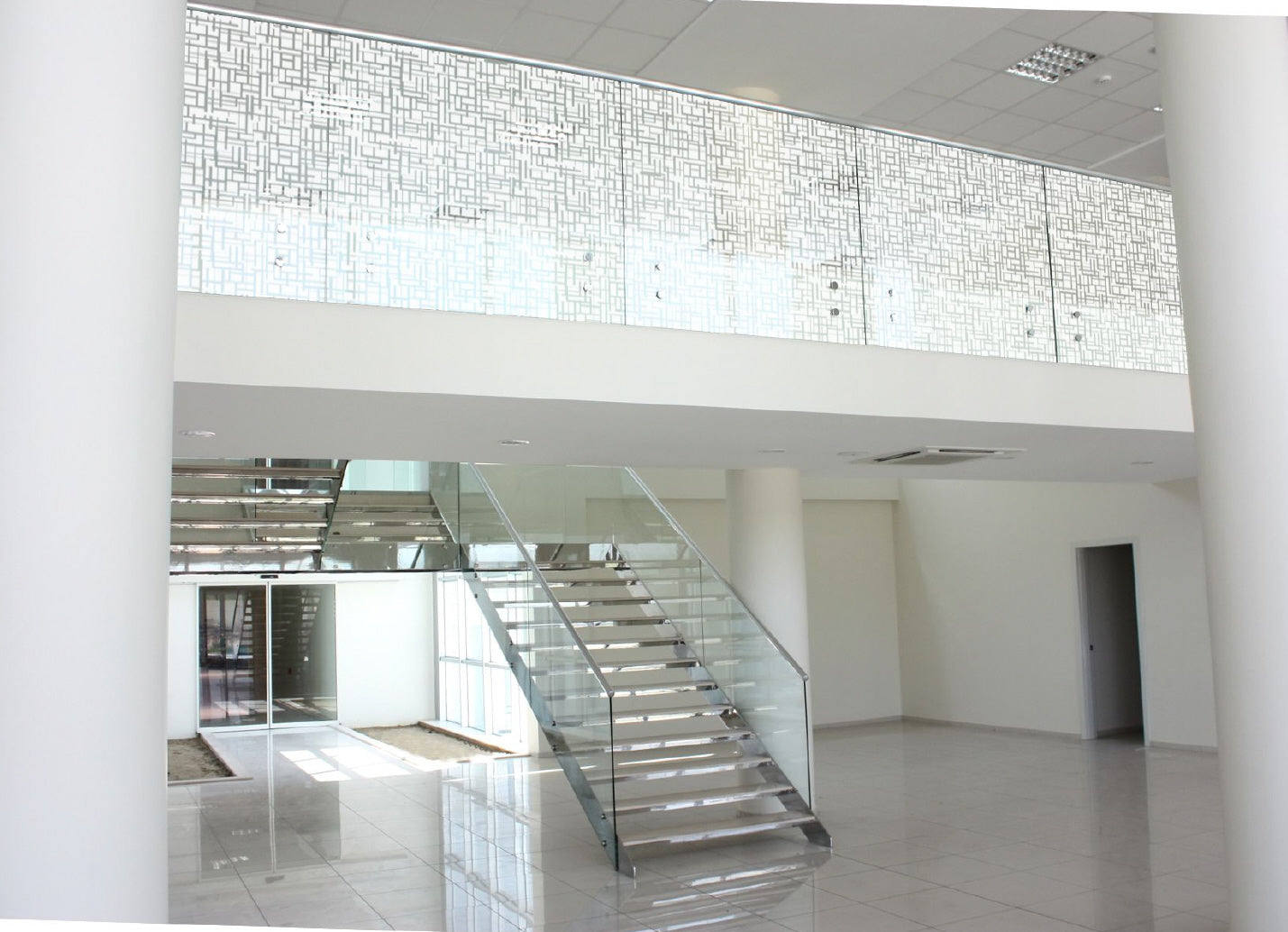 Moderne Treppe mit Glasgeländer und dekorativer Fensterfolie für Sichtschutz in Bürogebäude
