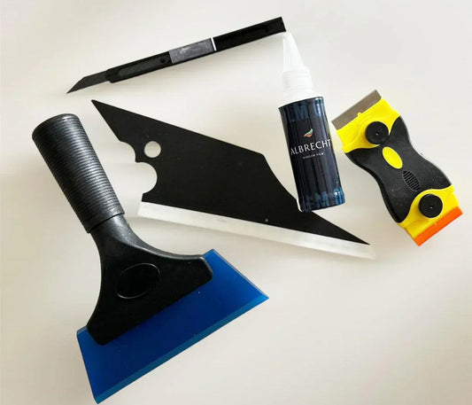 Montageset für Fensterfolie mit Rakel, Cutter, Sprühflasche und Schaber auf weißem Hintergrund