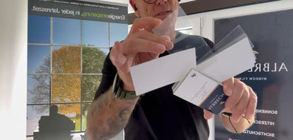 Mann zeigt Musterfächer mit Splitterschutzfolien für Fenster im Innenraum