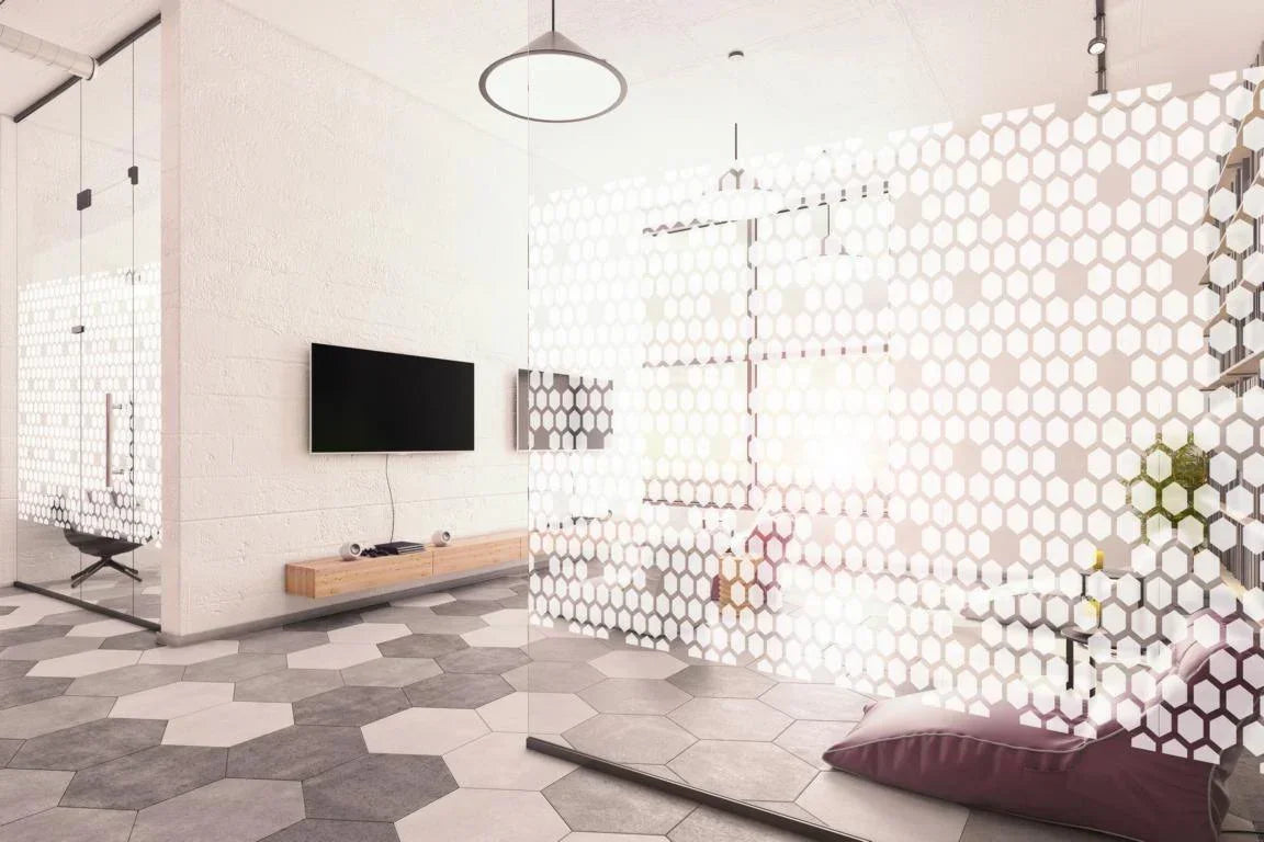 Moderne Fensterfolie mit Wabenmuster auf Glaswand in hellem Büro mit TV und Sitzkissen