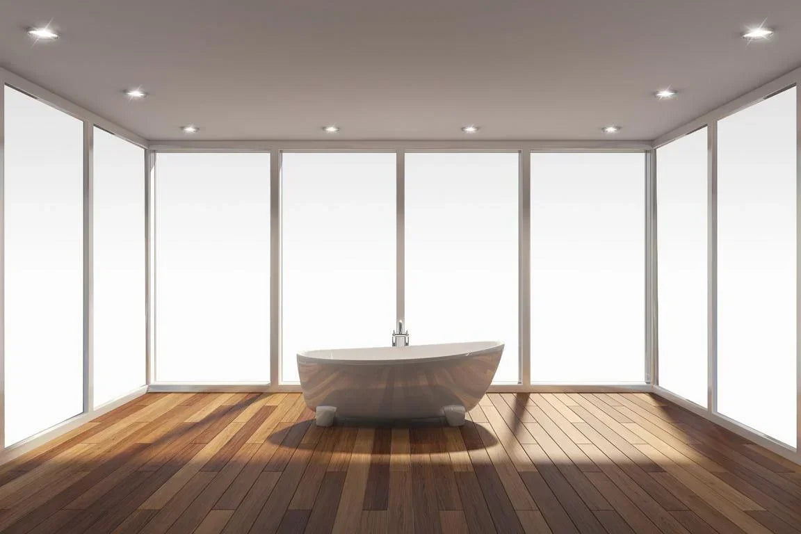Moderne Badewanne vor großen Fenstern mit milchiger Fensterfolie, heller Holzfußboden