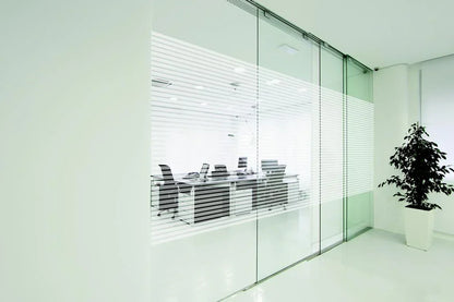 Moderne Bürotrennwand mit dekorativer Fensterfolie in Streifenoptik, Konferenzraum sichtbar