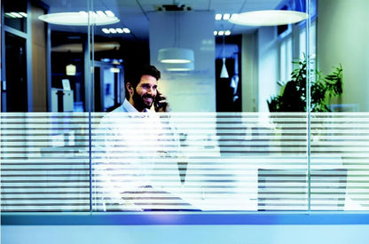 Dekorative Fensterfolie mit Streifenmuster als Sichtschutz in modernem Büro, Mann telefoniert